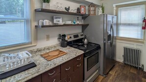 Una cocina con encimera de granito, electrodomésticos de acero inoxidable, armarios de madera y un cartel que dice "COFFEE TIME".