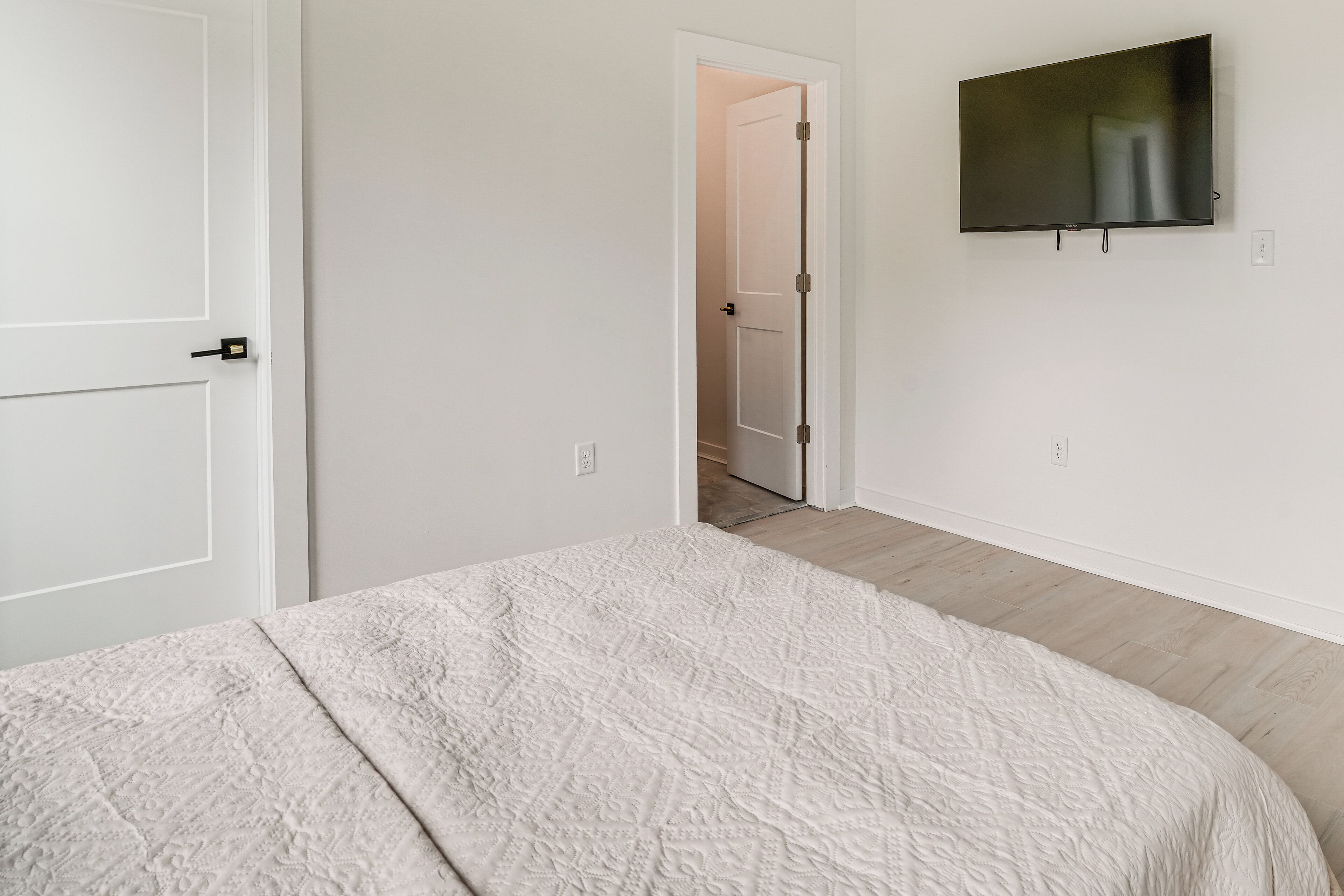Una camera da letto con un letto, una porta, una televisione e un corridoio.