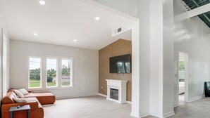 A spacious living room with a sectional sofa, a fireplace, and a flat-screen TV mounted on a wooden wall. - Close to Ohio River: 6BR Jeffersonville Home (Jeffersonville)