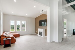 A spacious living room with a sectional sofa, a fireplace, and a flat-screen TV mounted on a wooden wall. - Close to Ohio River: 6BR Jeffersonville Home (Jeffersonville)