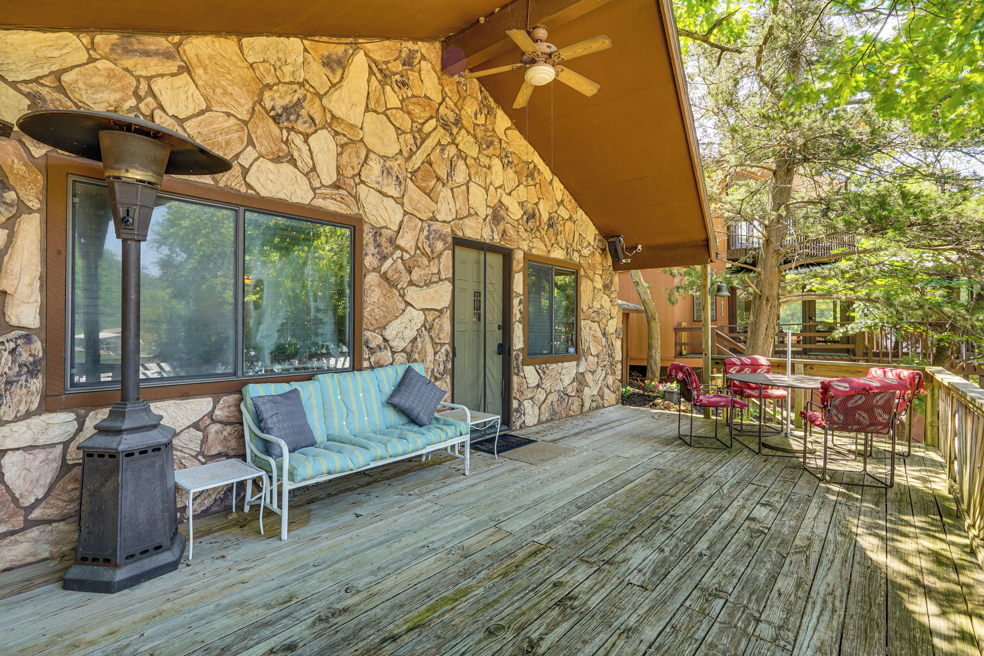 A stone exterior with a covered deck, outdoor seating, and a patio area.