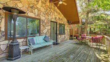 A stone exterior with a covered deck, outdoor seating, and a patio area.