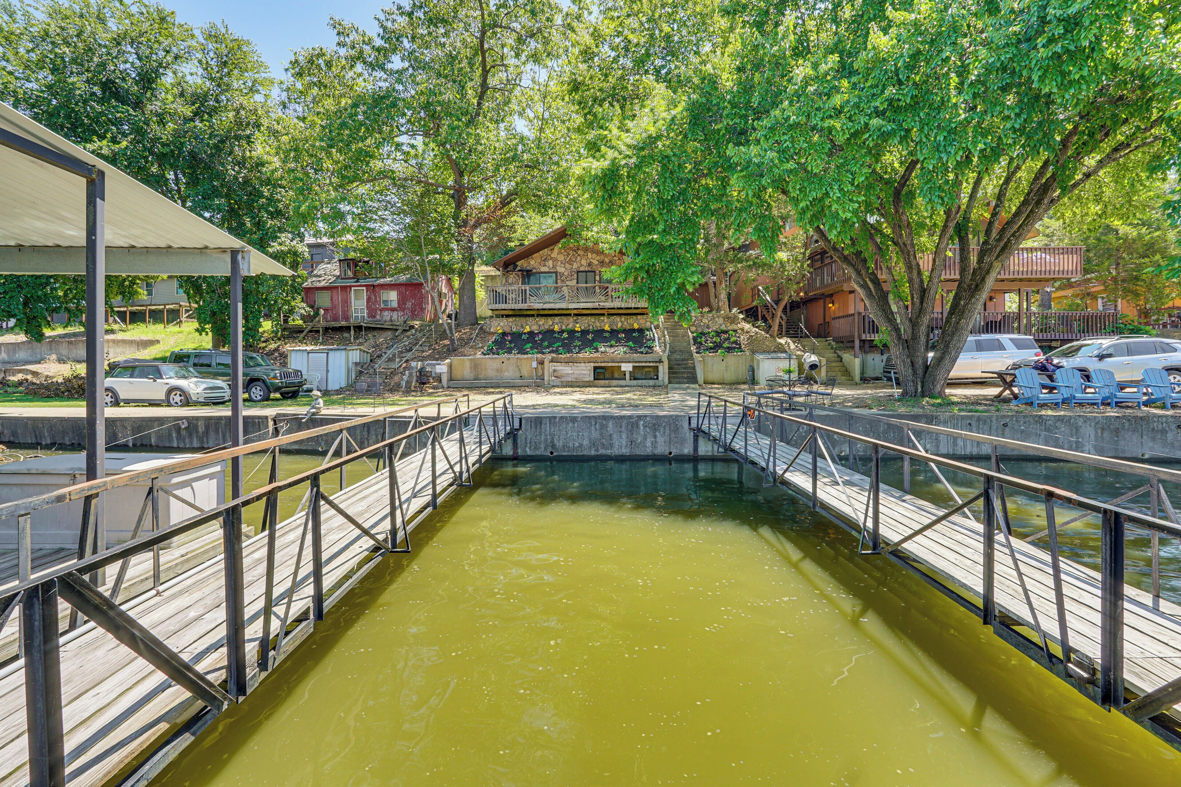 A wooden bridge over a body of water, surrounded by trees and buildings.