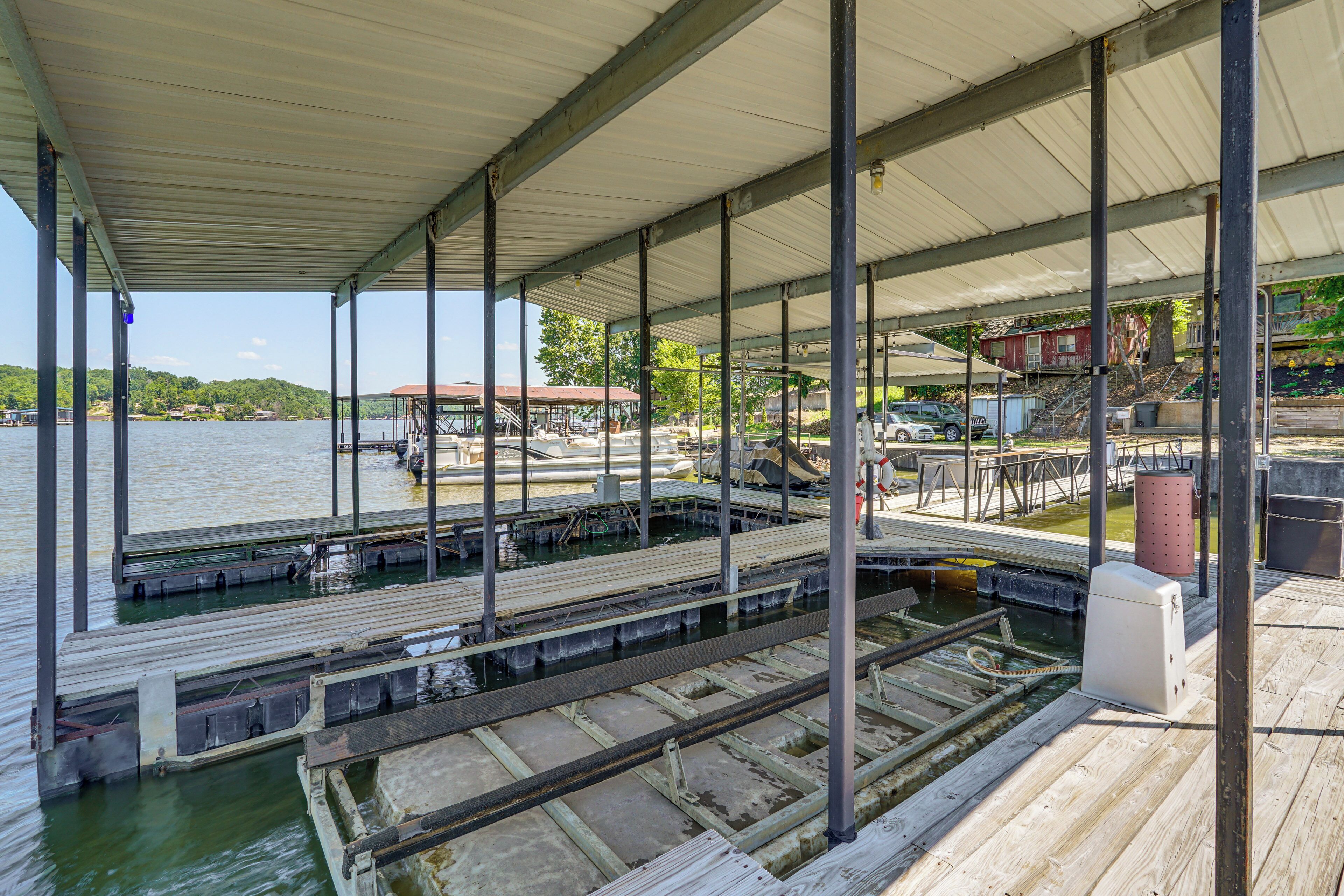 Un muelle techado con vistas al agua, un rampa para embarques y un pequeño edificio al fondo.