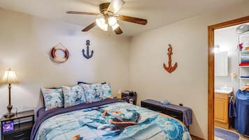 A bedroom with a bed, a ceiling fan, and nautical-themed decor.