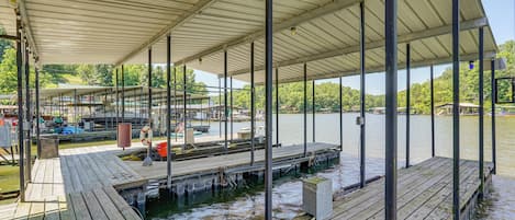 A covered dock area with a view of the water and a boat in the background.