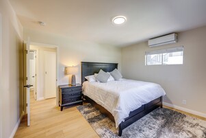 Un dormitorio con cama, mesita de noche, lámpara y equipo de aire acondicionado.