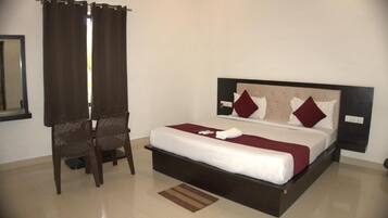A hotel room with a bed, a chair, a nightstand, and a mirror.