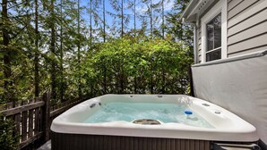 A hot tub in a backyard with a wooden deck and a house in the background. - Seabrook Feelin TipSEA | Hot Tub, Dual Suites, 2BR | Sleeps 4, Lily Walk (Pacific Beach)