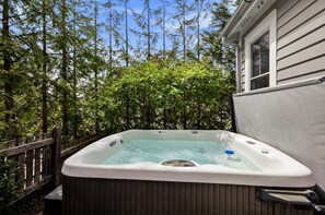 Ein Whirlpool in einem Garten mit einer Holzterrasse und einem Haus im Hintergrund.