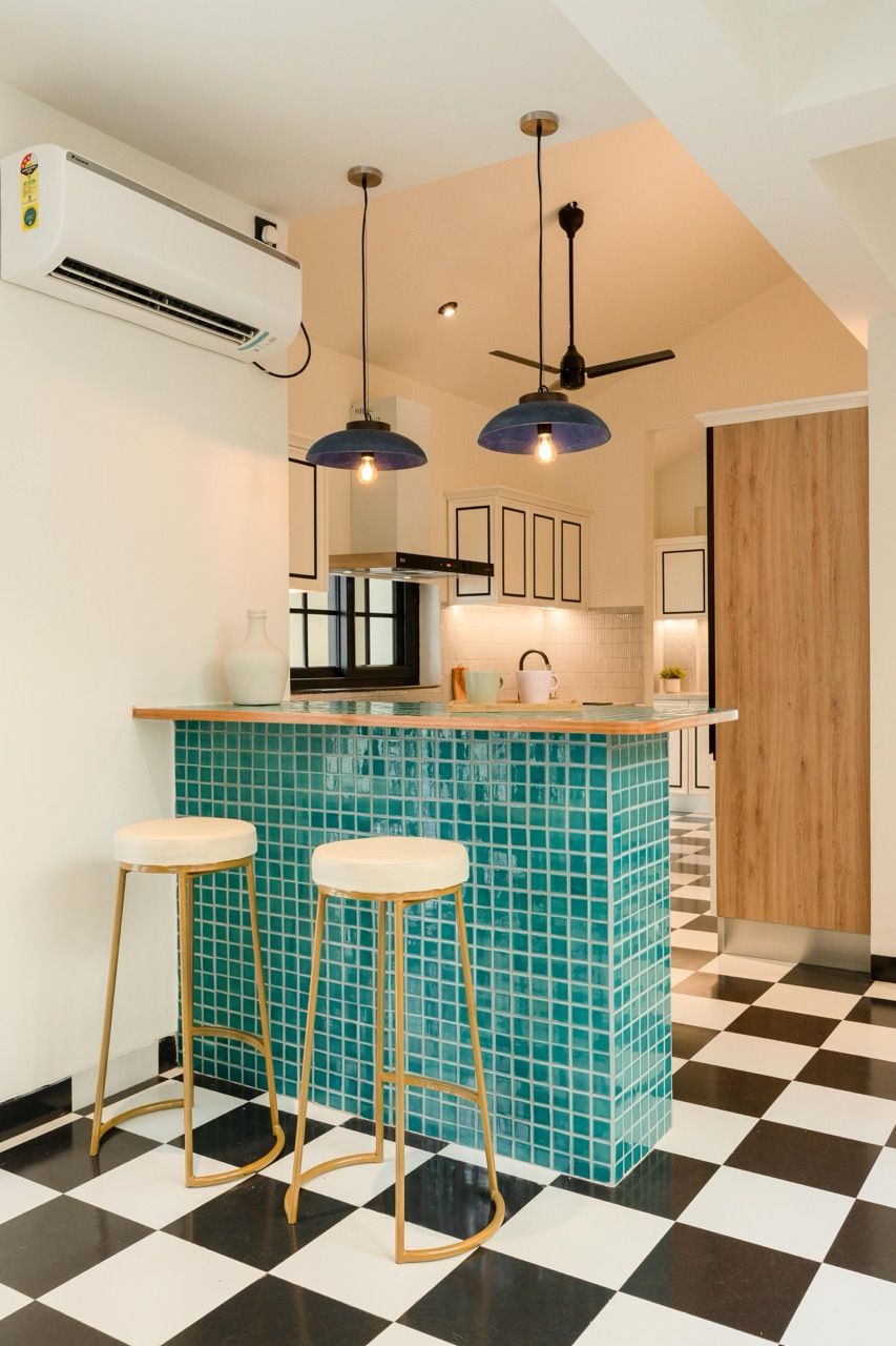 A kitchen with a checkered floor, a blue tiled island, two stools, and pendant lighting.