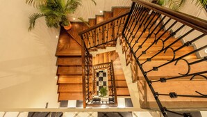 A wooden staircase with a metal railing, leading to a checkered floor. - Staymaster Abira-3BR Pvt Pool Villa (Assagao)