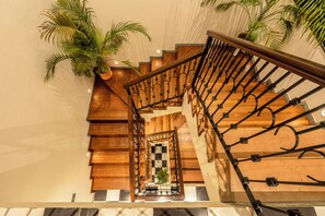 A wooden staircase with a metal railing, leading to a checkered floor. - Staymaster Abira-3BR Pvt Pool Villa (Assagao)