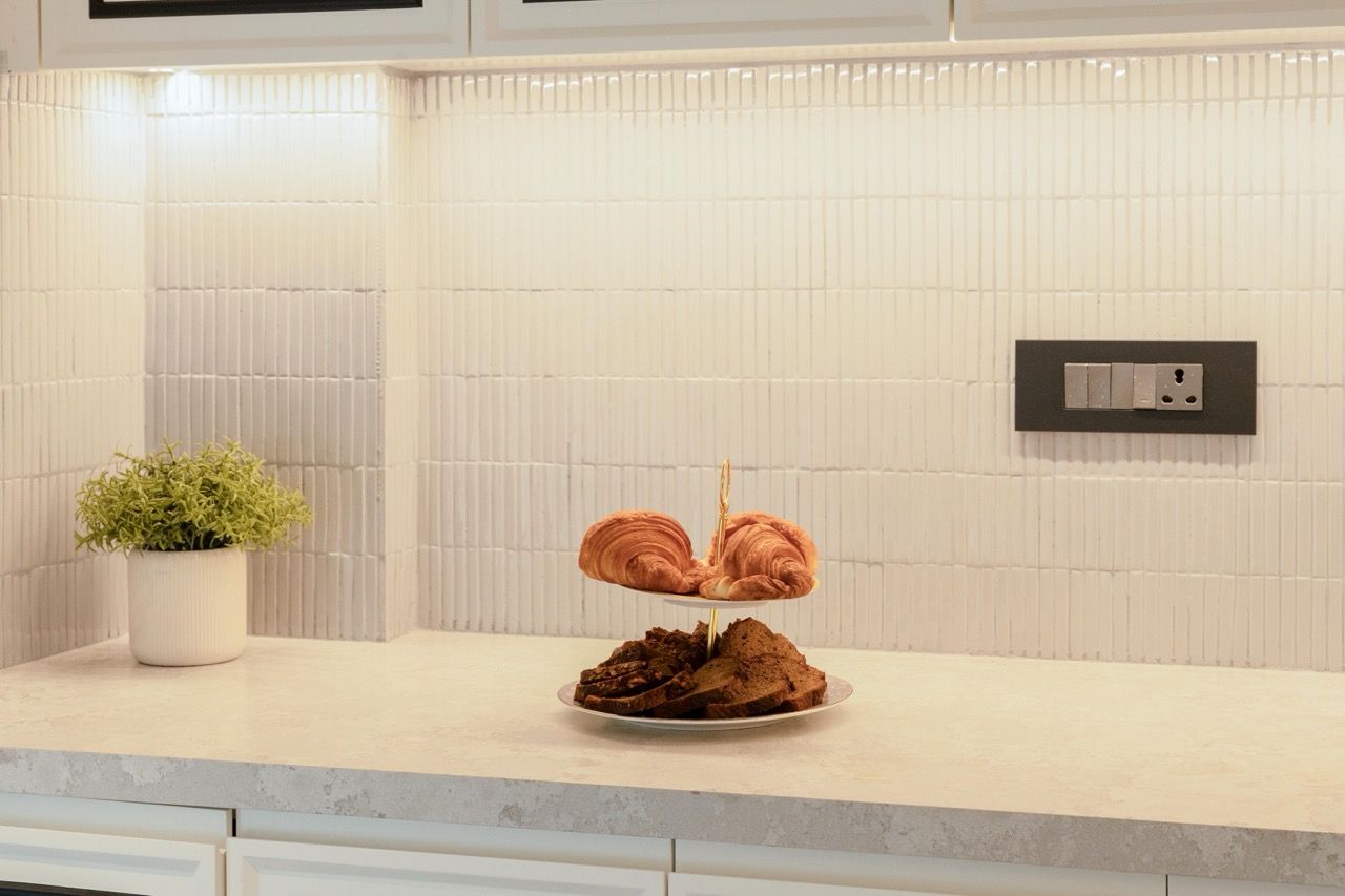 A kitchen counter with a two-tiered stand holding croissants and a potted plant.