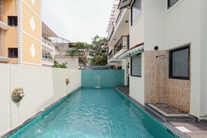 A swimming pool with a tiled border, a lion head water feature, and a wooden door. - Staymaster Abira-3BR Pvt Pool Villa (Assagao)