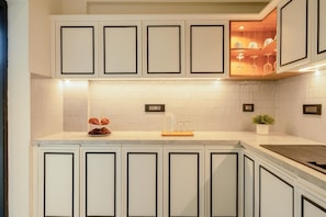 A kitchen with white cabinetry, a tiled backsplash, and a countertop with a plant and a glass jar. - Staymaster Abira-3BR Pvt Pool Villa (Assagao)