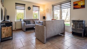 A living room with a sofa, a television, and a fireplace. - Villa Texel With Sauna (De Koog)