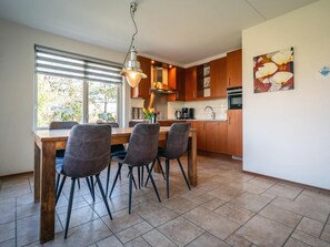 Une cuisine moderne avec des meubles de rangement en bois, une table à manger avec des chaises et un luminaire suspendu.