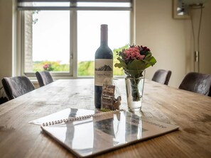 A wooden table with a wine bottle, a glass of flowers, and a chocolate bar. - Villa Texel With Sauna (De Koog)