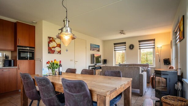 A modern kitchen with a dining area, wooden table, and chairs. - Villa Texel With Sauna (De Koog)