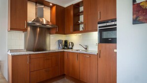 A modern kitchen with wooden cabinets, stainless steel appliances, and a tiled backsplash. - Villa Texel With Sauna (De Koog)