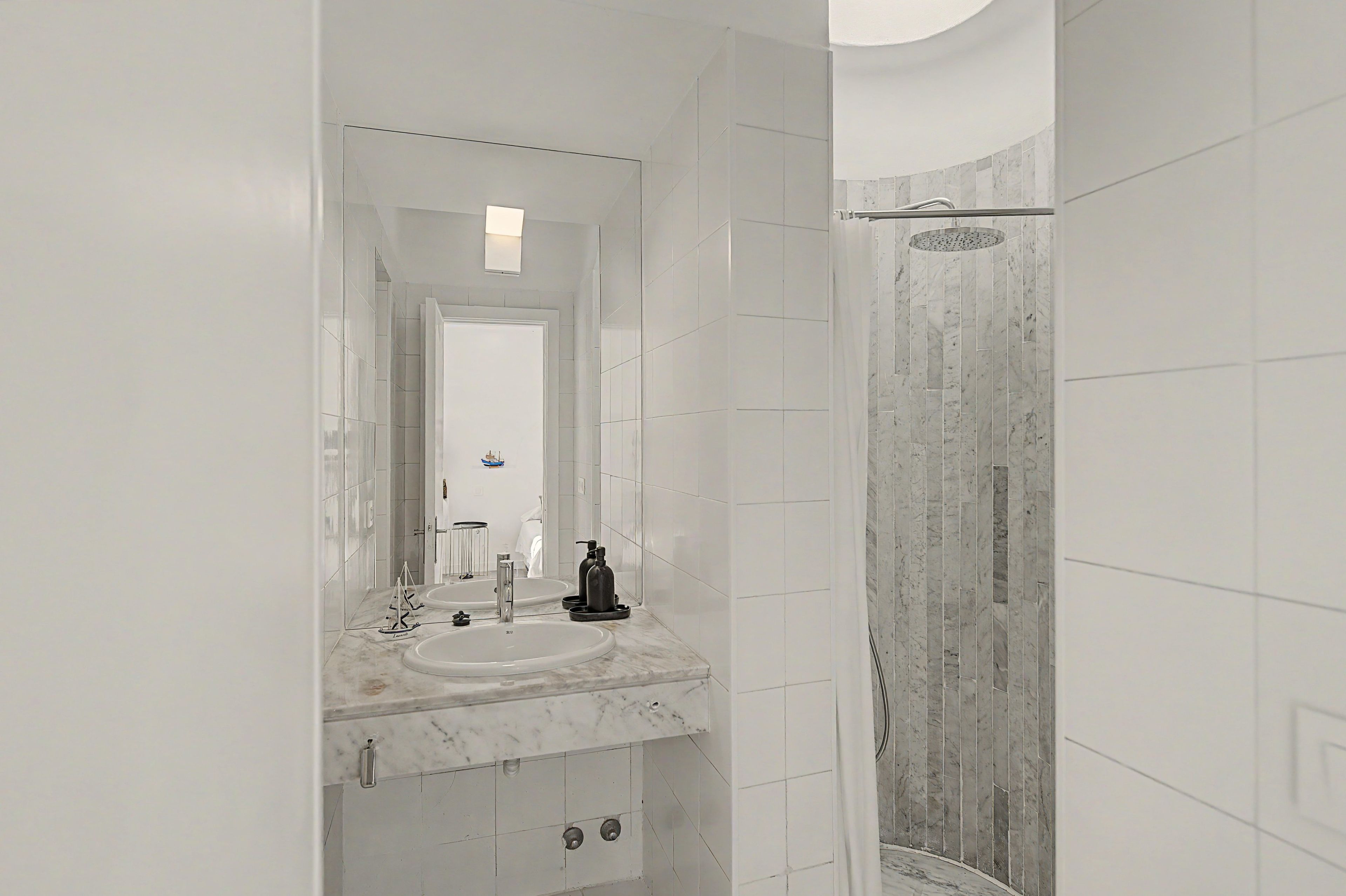 A modern bathroom with a large mirror, a sink, and a shower area.