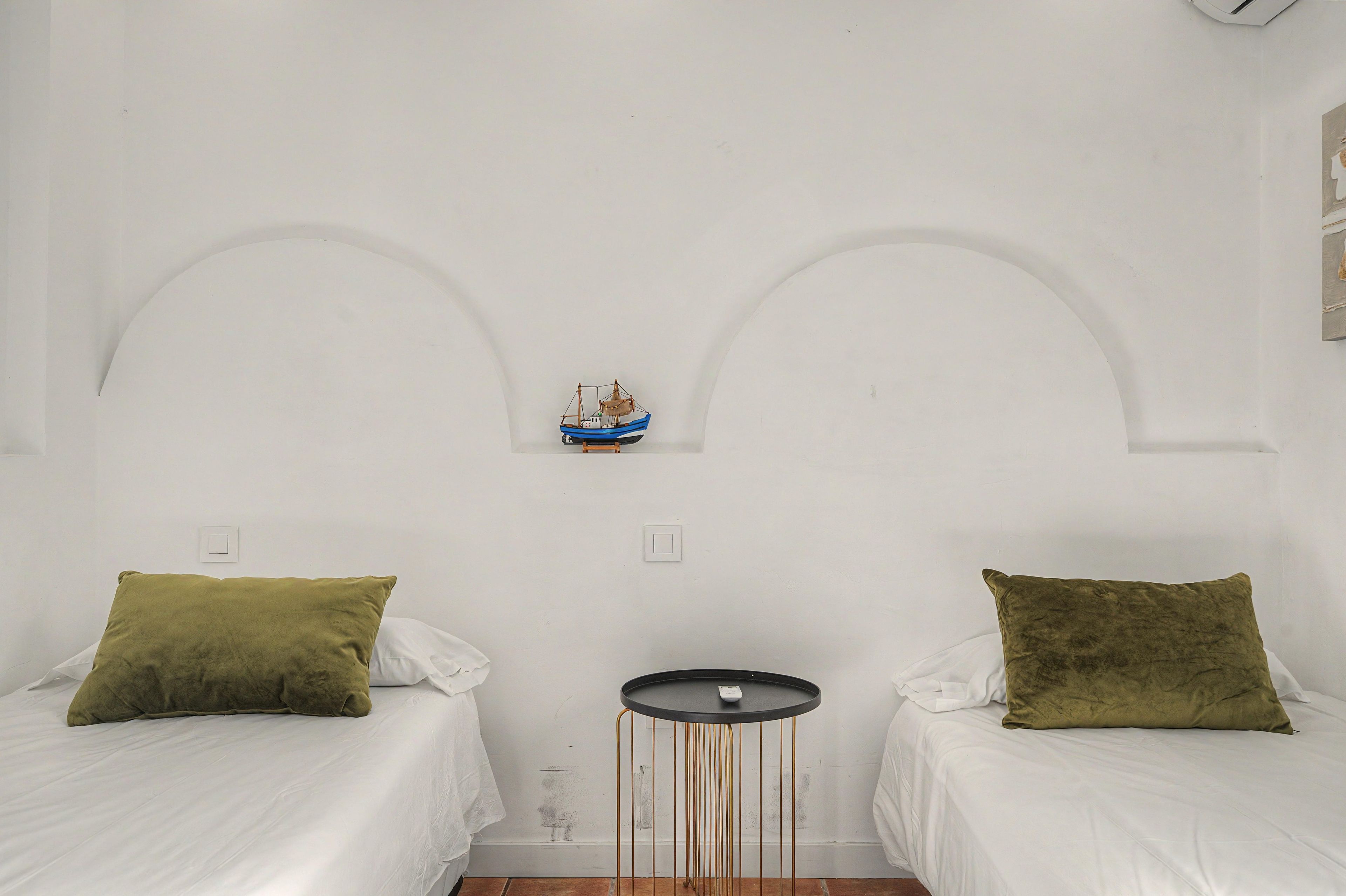 Ein Schlafzimmer mit zwei Betten, einem kleinen runden Tisch und einem dekorativen Schiffsmodell an der Wand.