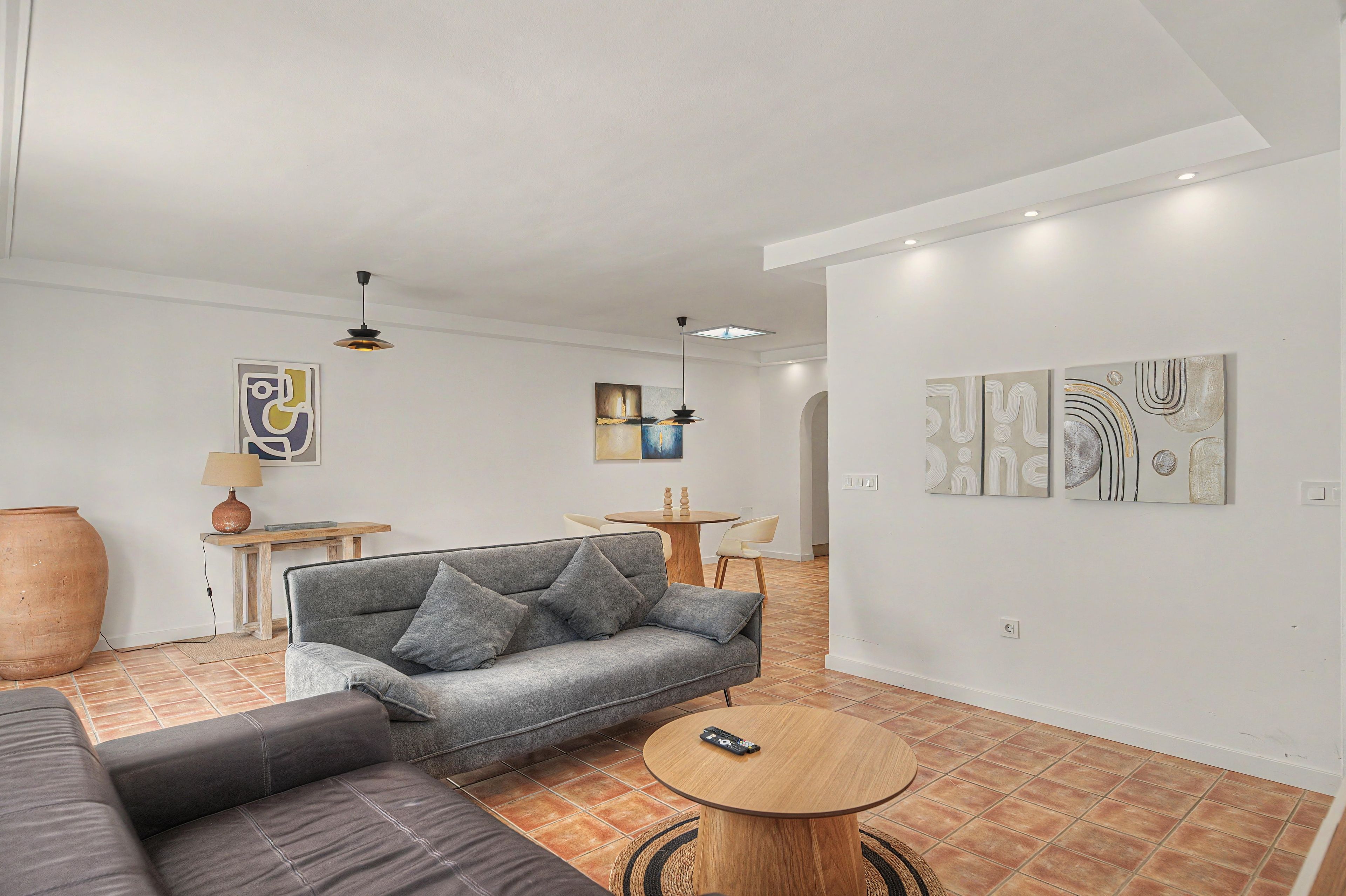Una sala de estar moderna con un sofá gris, una mesa redonda de centro y obras de arte en las paredes.