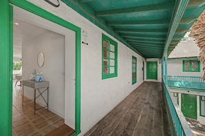 A corridor with green-framed windows and doors, a small table with a vase, and a wooden floor. - César’s Oasis – Manrique-Style Architecture Near Playa de las Cucharas (Costa Teguise)
