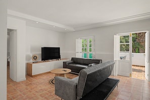 Ein modernes Wohnzimmer mit Flachbildfernseher, grauem Sofa und Couchtisch.