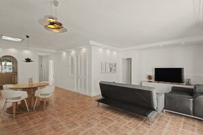 Una sala moderna con un sofá, televisión y comedor con sillas y una mesa.