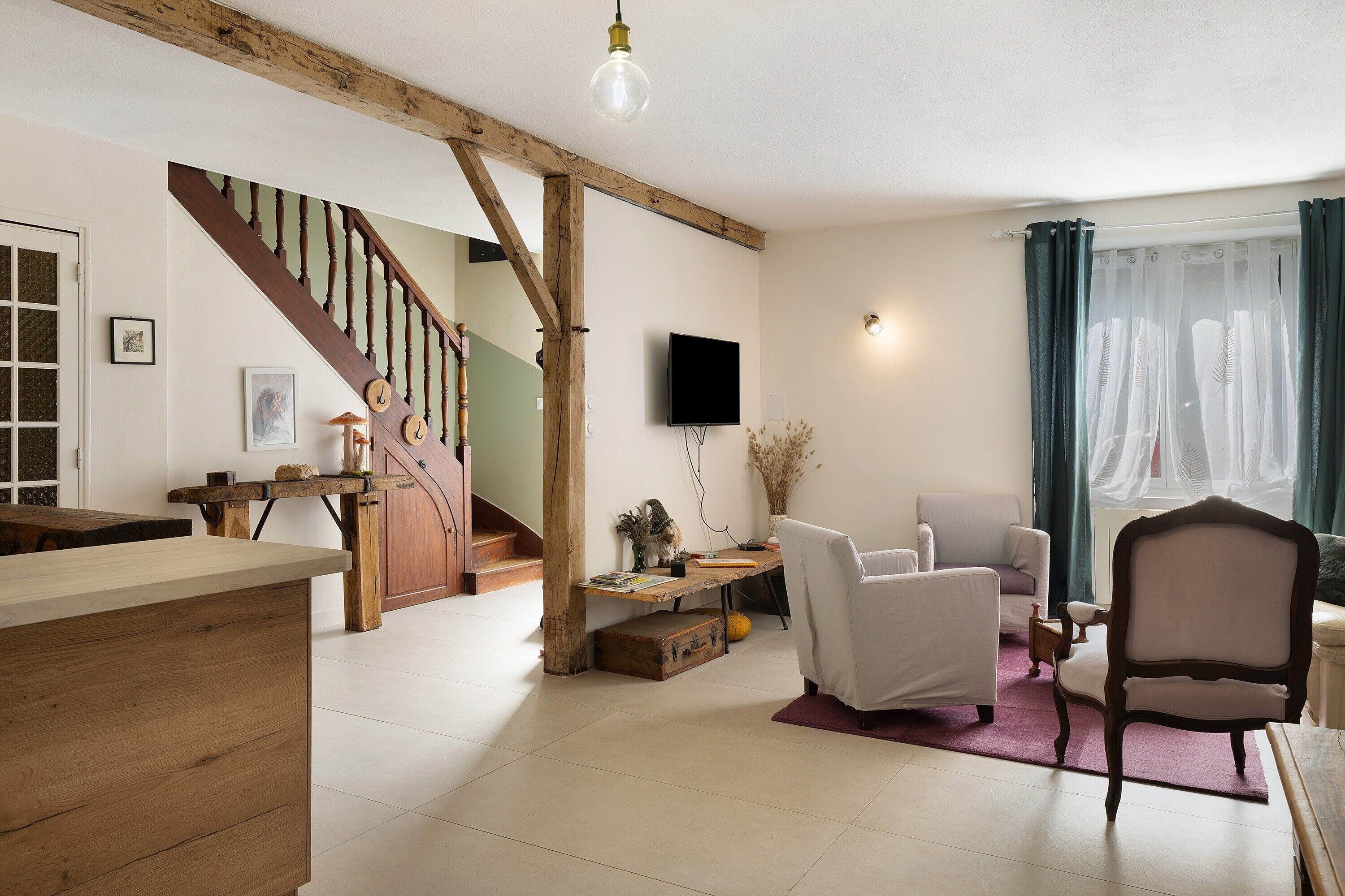 A spacious living room with a wooden staircase, a flat-screen TV, and a comfortable seating area.