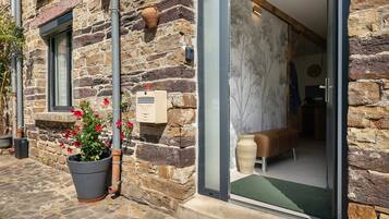 A stone building with a door leading to a room with a bench and a wall-mounted clock.