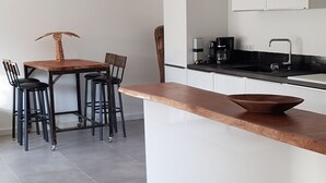 Eine moderne Küche mit einer zentralen Kochinsel, einem Essbereich mit Stühlen und einer Kaffeemaschine.