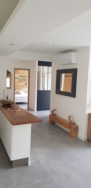 A modern interior with a wooden bench, a white cabinet, and a wall-mounted air conditioner. - Garden-Level Apartment (Sainte-Maxime)