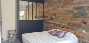 A bedroom with a bed, a mirror, and a wall with wooden planks. - Garden-Level Apartment (Sainte-Maxime)