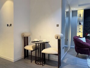 A modern interior with a round table, two chairs, a purple sofa, and a decorative shelf with items. - Stylish 1BR in Lekki 1 ~ 24/7 Power & Fast WiFi (Lekki)