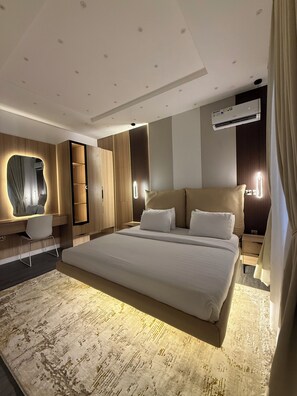 A modern hotel room with a large bed, built-in wardrobe, bedside tables, and a wall-mounted air conditioning unit. - Stylish 1BR in Lekki 1 ~ 24/7 Power & Fast WiFi (Lekki)