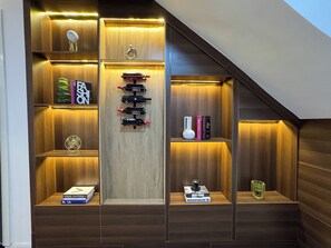 A wooden staircase with shelves containing books, wine bottles, and decorative items. - Stylish 1BR in Lekki 1 ~ 24/7 Power & Fast WiFi (Lekki)