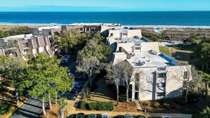 A coastal hotel with multiple buildings, parking, and a view of the ocean. - Sunset Rentals | Island Club 6102 (Hilton Head Island)