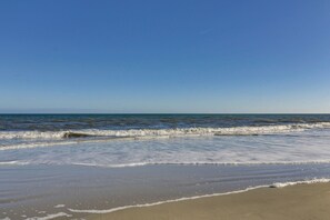 Ein Strand mit sanft anschwellenden Wellen unter blauem Himmel.