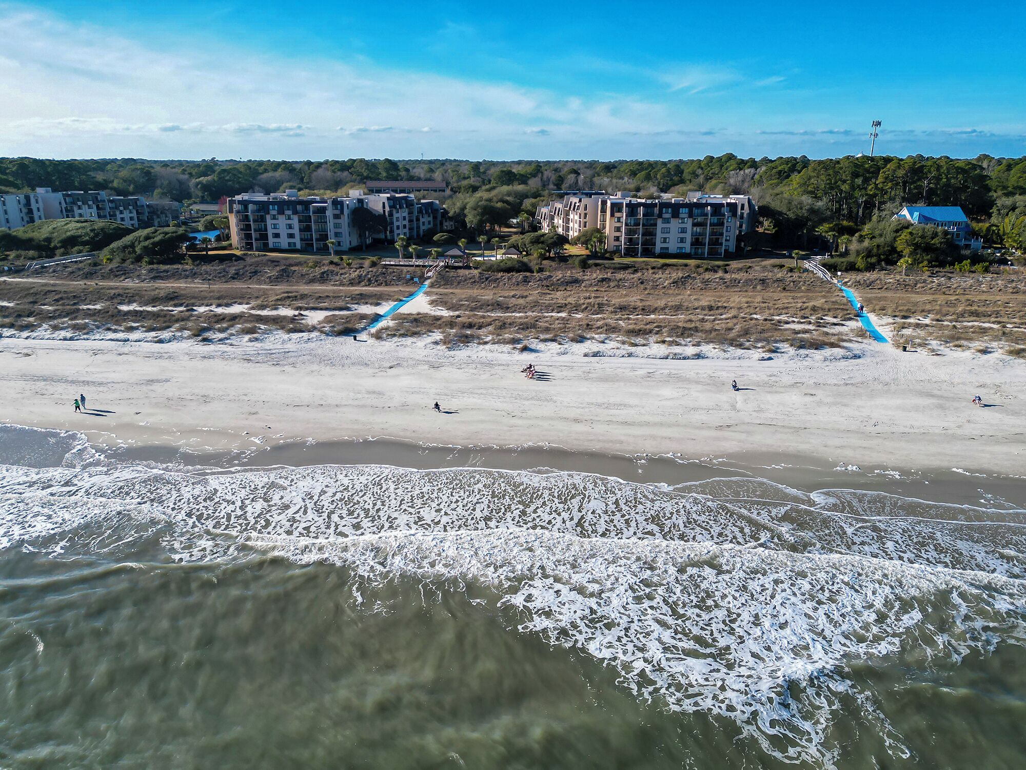 A beach with a clear view of a multi-story building in the background.