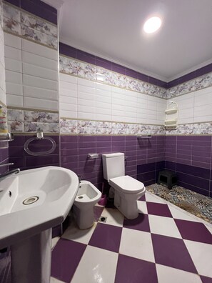 Un baño con lavamanos, bidé, inodoro y espejo.