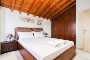 A bedroom with a wooden ceiling, a large bed, a wardrobe, and two wall-mounted paintings. - Venetia Beach House by Rentals Pro - Mouries Halkidiki (Mouries)
