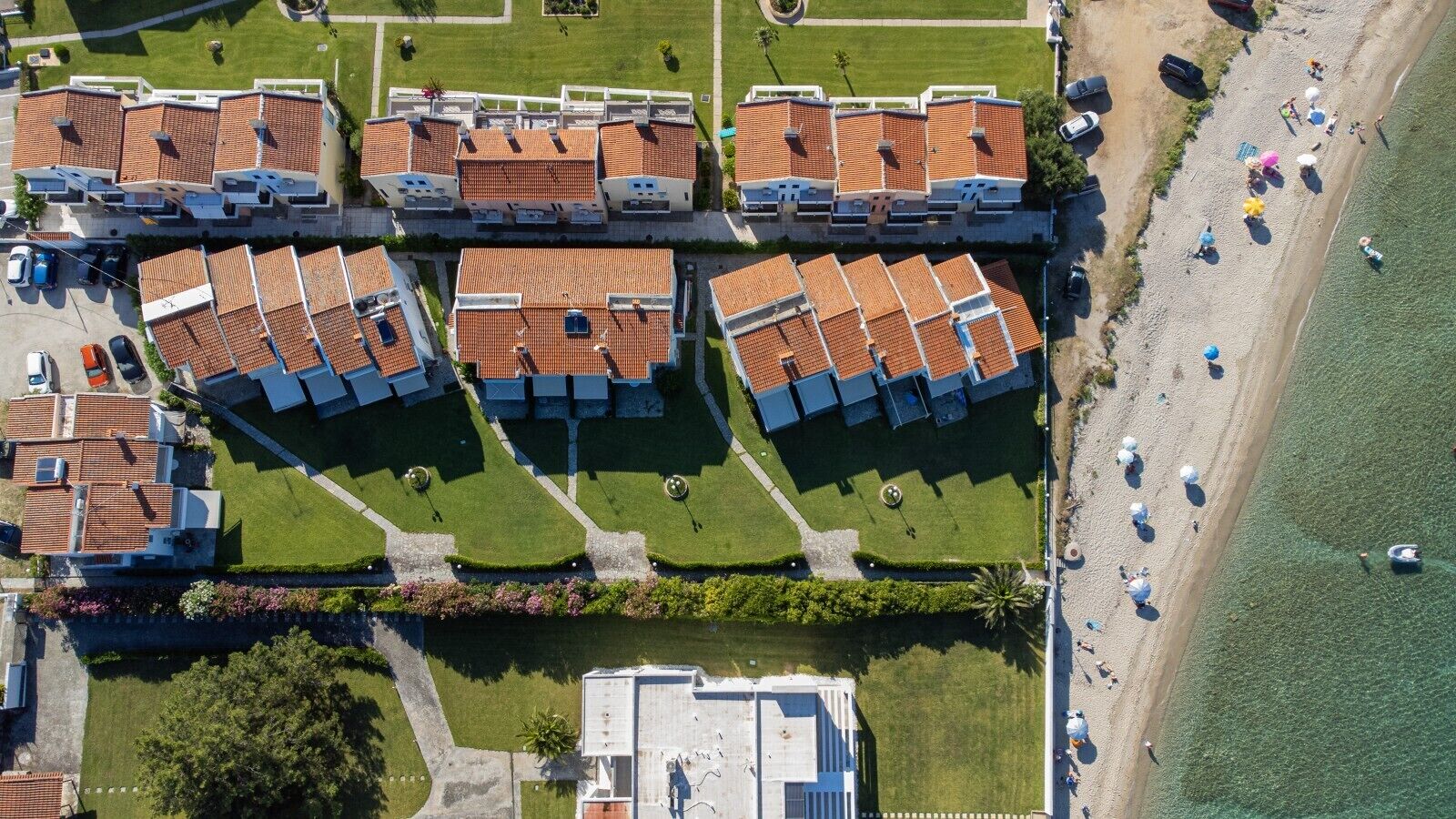Un quartier résidentiel situé sur la côte, avec des maisons en terrasses, une plage et un port de plaisance.