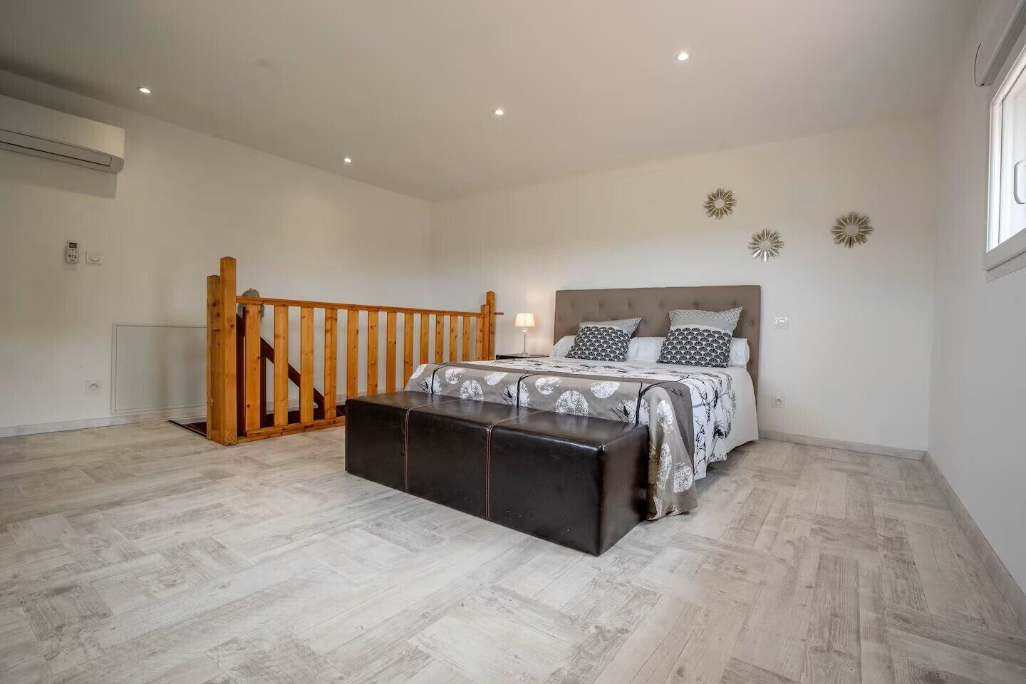 Una camera da letto con un letto, una scala in legno, una panca e una lampada a soffitto.