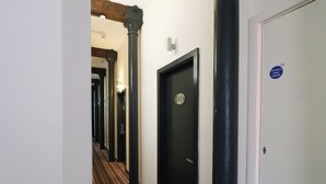 A hallway with black doors, a striped carpet, and a fire door sign. - Apartment 610 (Nottingham)