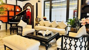 A living room with a piano, sofa, coffee table, and decorative items. - Dollar Hotel An Khanh (Hanoi)