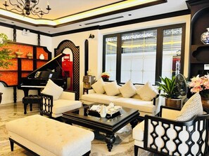 A living room with a piano, sofa, coffee table, and decorative items.
