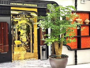 A building facade with a large potted plant in the foreground.